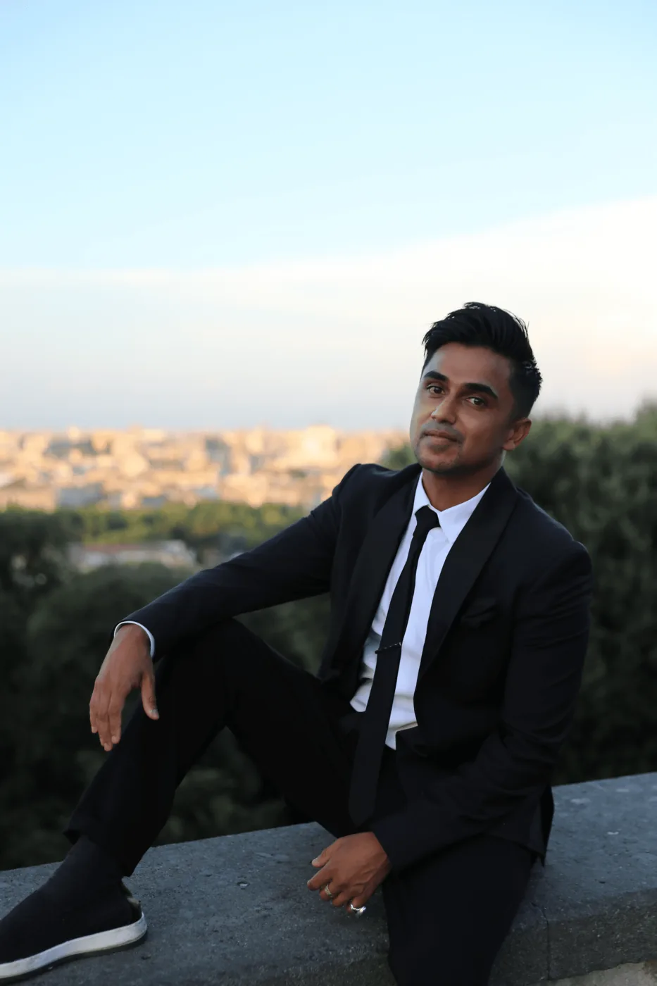 Nabeel in a suit, seated outdoors.