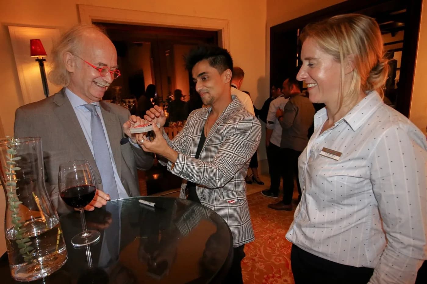 Guests watch Nabeel perform a card trick at a reception.