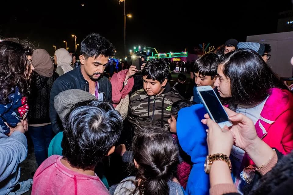 A group of guests, including children, watch Nabeel perform.