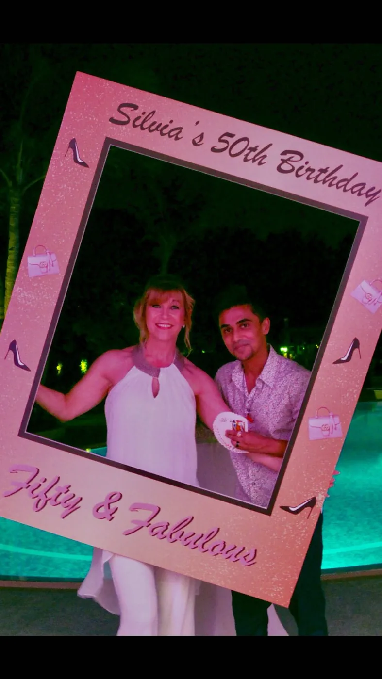 Two people pose behind a birthday celebration photo frame.