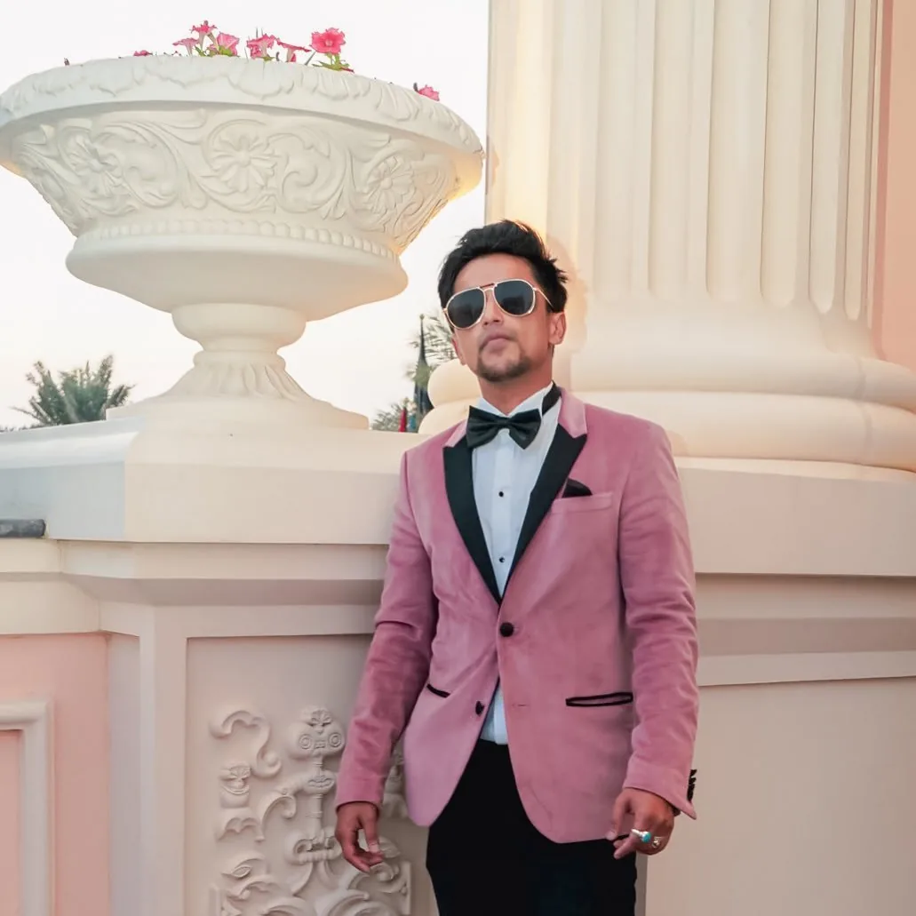Nabeel in a pink jacket beside a fountain.