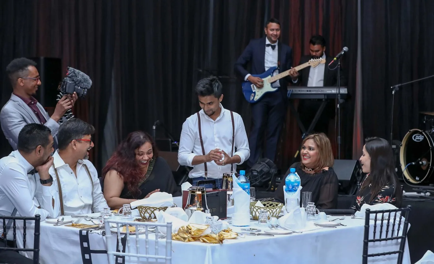 Nabeel performs among guests at a long outdoor dinner table.